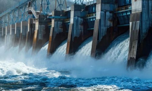 Hydropower dam releasing water with visible turbines and spillways, generating renewable energy.